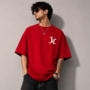 Red oversized T-shirt featuring a bold white JC logo, styled on a male model for Jatt Clothing's streetwear collection.