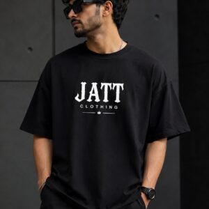 A male model wearing a black oversized Jatt Clothing T-shirt with the JATT CLOTHING logo, posing against a dark urban background.